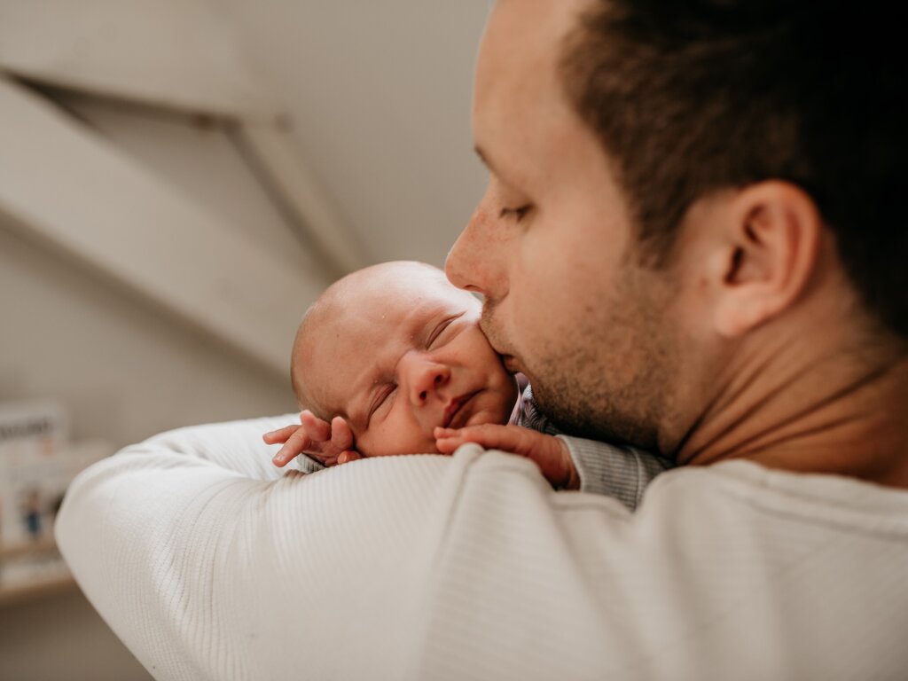 Warme gezinsmoment buiten — ouders en kind in zacht natuurlijk licht