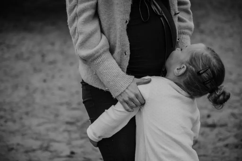 Detail bij een zwangerschapsshoot — handen op buik in zacht zijlicht