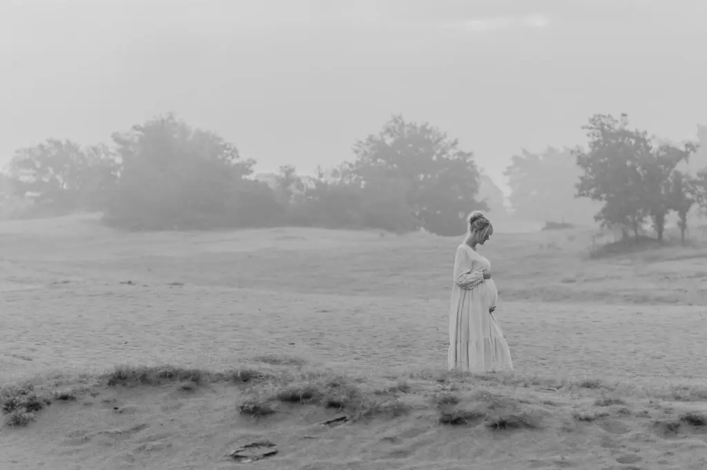 Zwangere vrouw silhouet op weidse zandvlakte bij zonsondergang